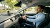 Homme conduisant une voiture sur une route arborée